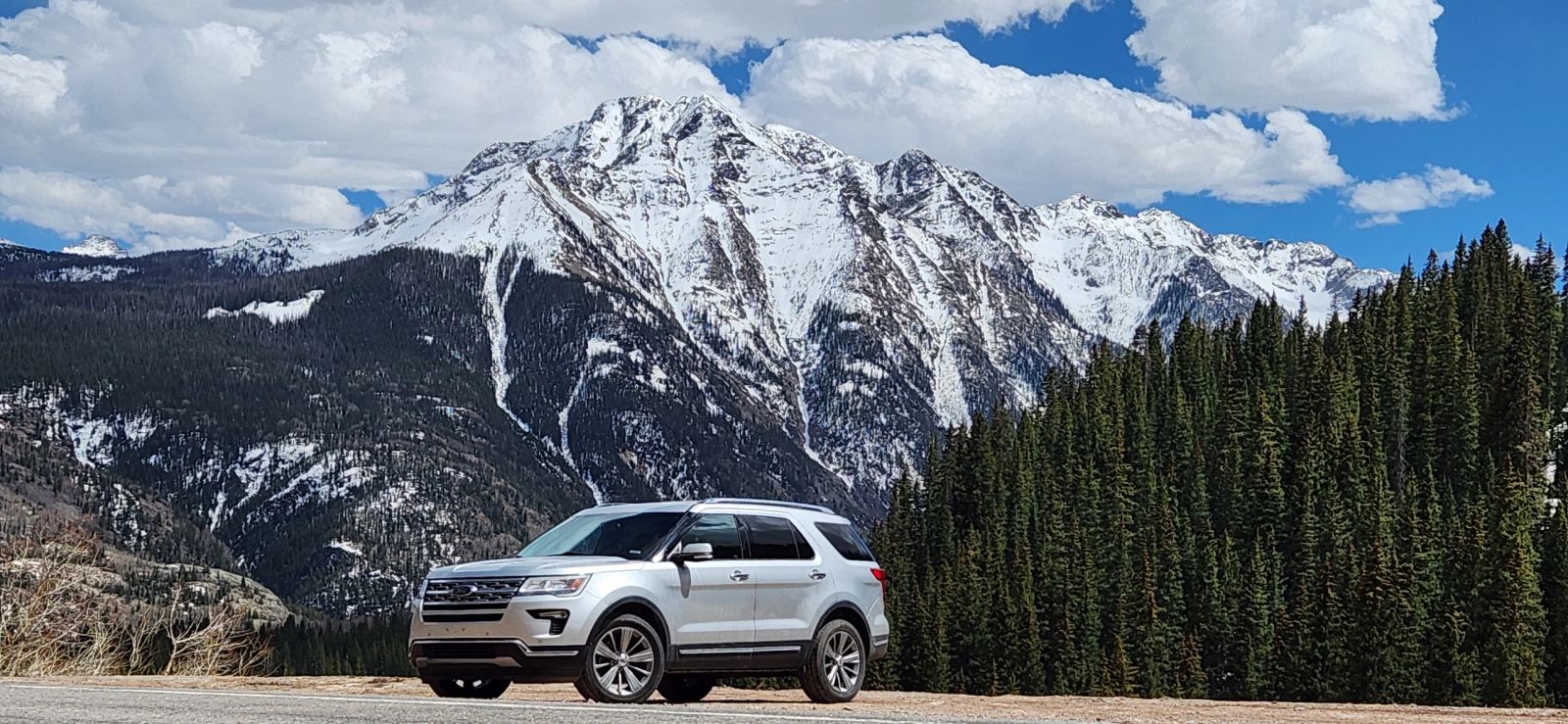 Summit Rental Car 2018 silver AWD Ford Explorer with snow tires on a mountain road near Breckenridge, Colorado